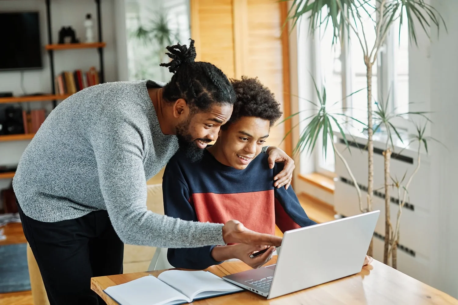 Young man showing younger boy something on laptop
