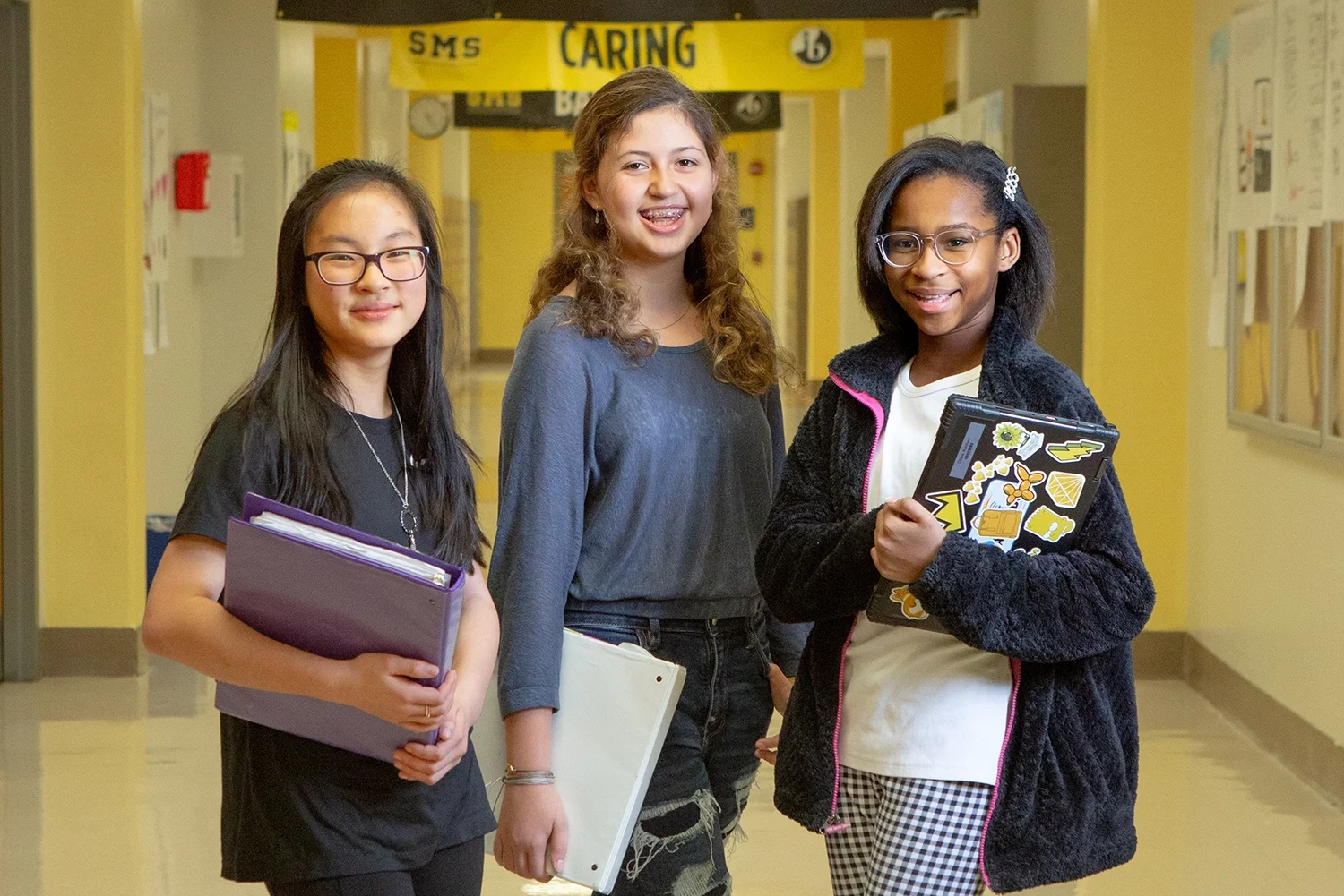 Three girls standing in school hallway